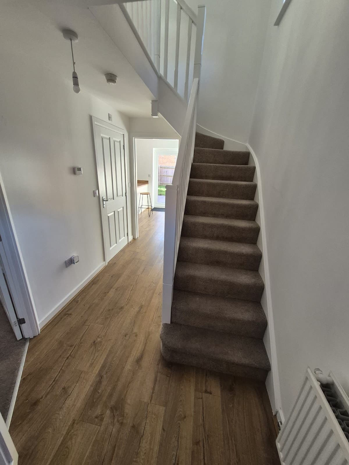 After — Full property renovation at 30 Thistle Way, Lincoln — hallway with new wood-effect flooring and carpeted stairs, tenancy ready