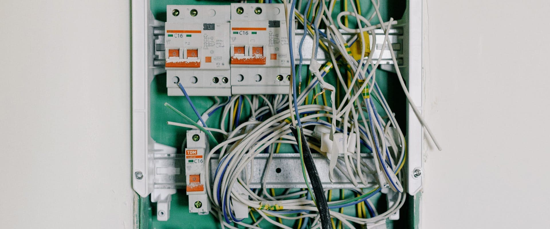 Opened electrical switchbox — qualified electrician carrying out an EICR inspection at a rental property