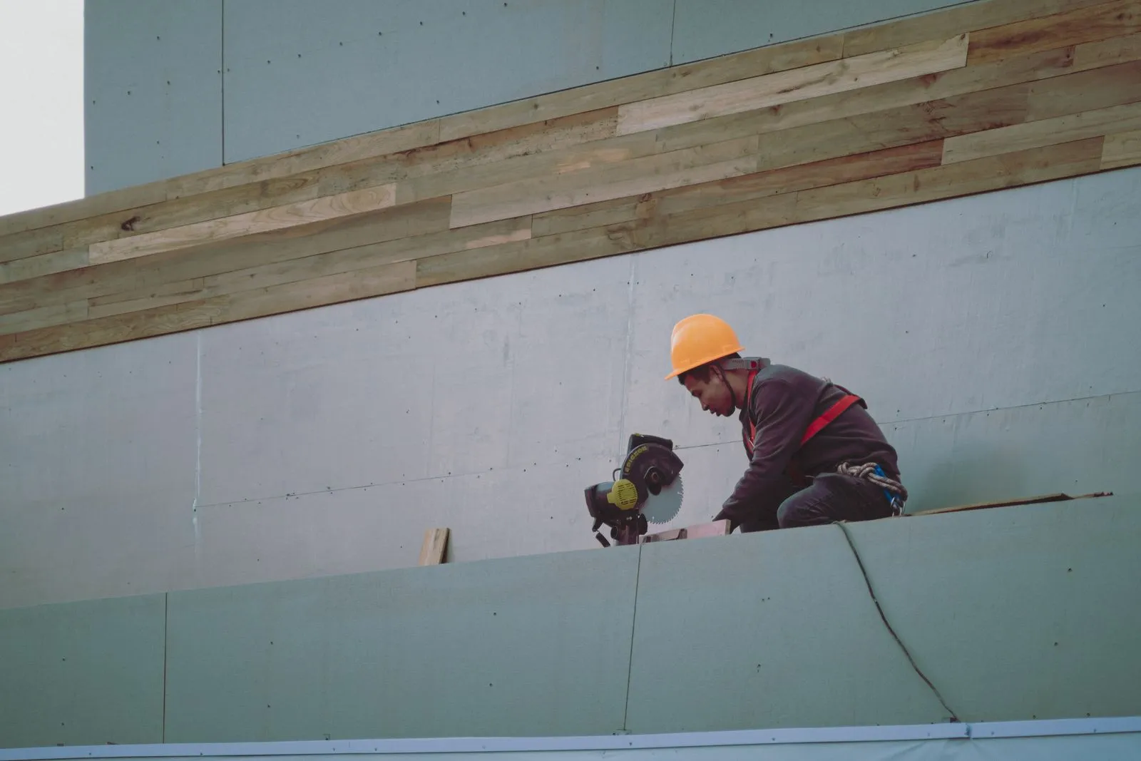 Maintenance contractor in safety gear working on the exterior of a commercial building, the kind of site work a Lincoln business books through an FM company or a local contractor