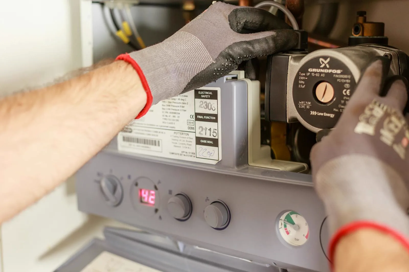 A qualified engineer inspecting a boiler and its electrical components during a safety certificate check in a rental property
