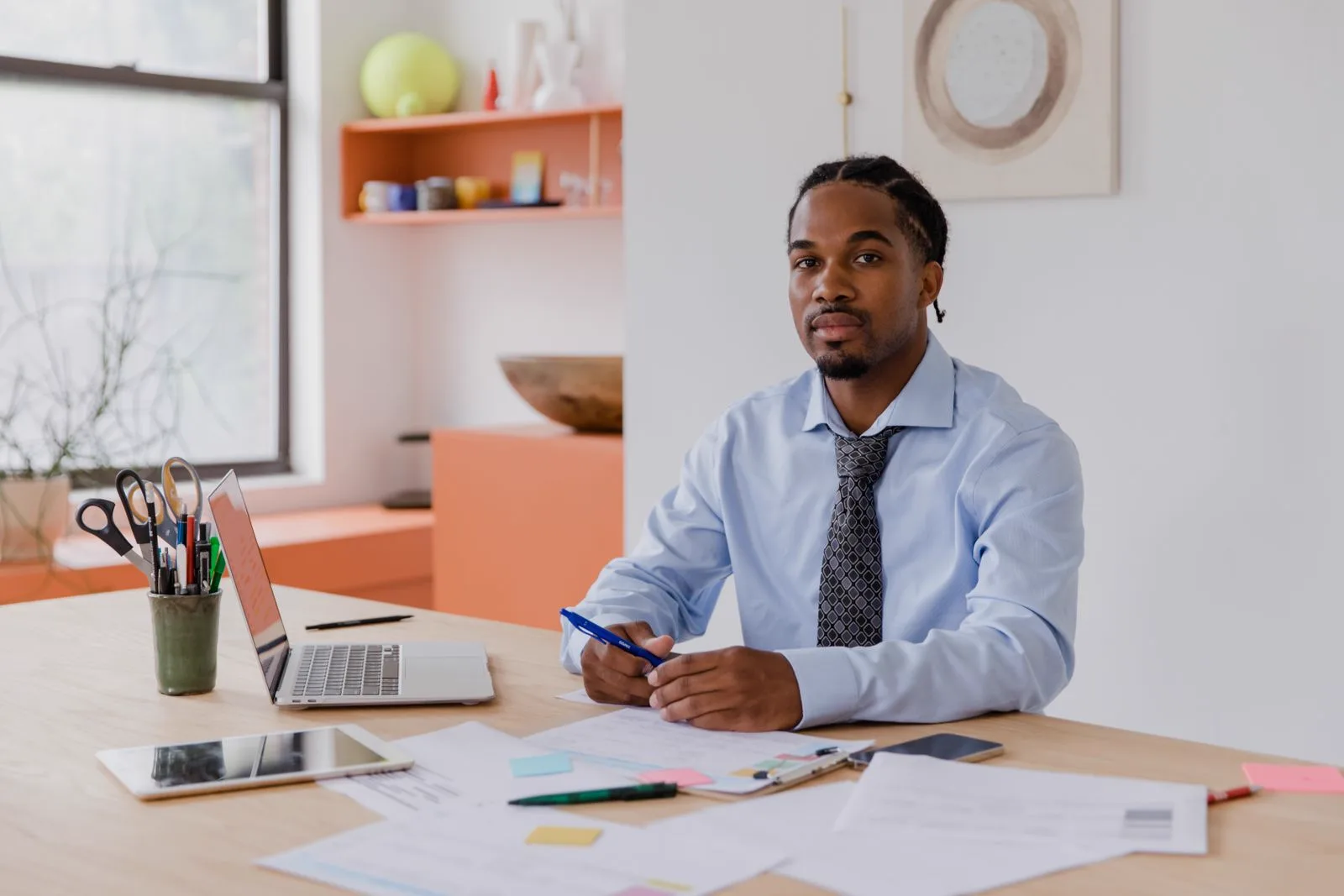 A landlord reviewing property documents on a laptop and tablet at an organised desk, in control of their maintenance admin
