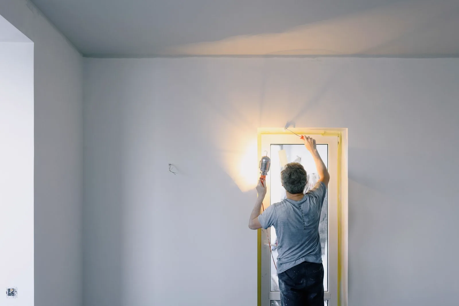 A tradesperson repairing a door frame in an empty rental property with tools laid out, representing reactive repairs between tenancies