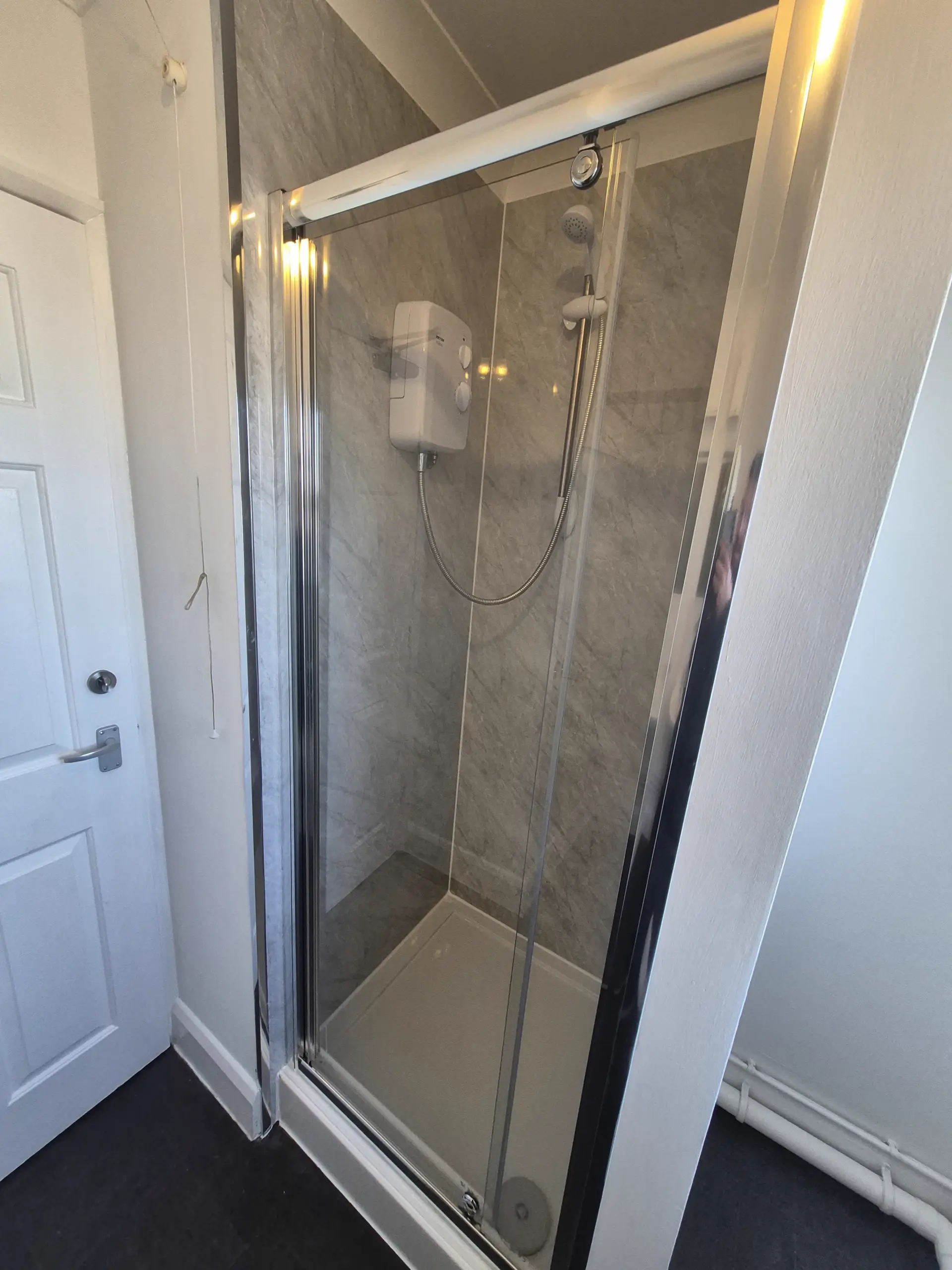 Clean shower enclosure with marble-effect panelling in a Lincoln rental property fitted by LWR Group