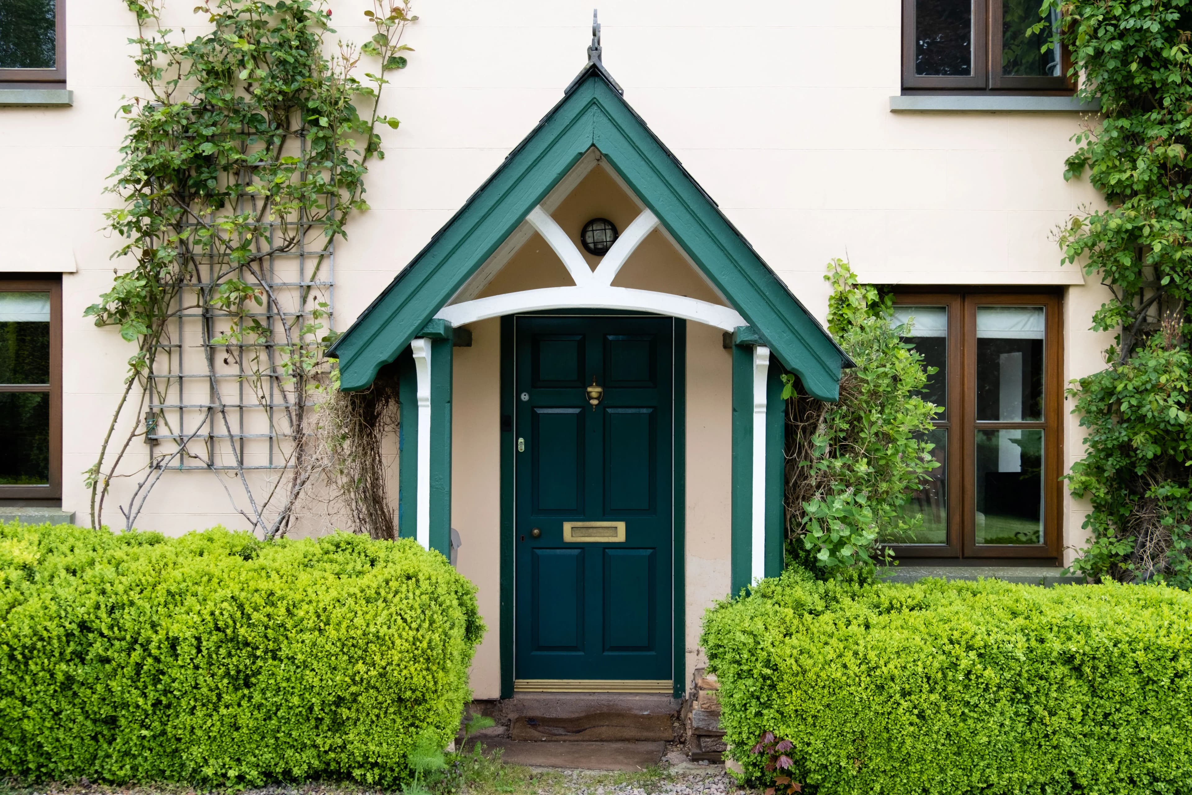 Neatly trimmed front garden hedges either side of a UK house entrance