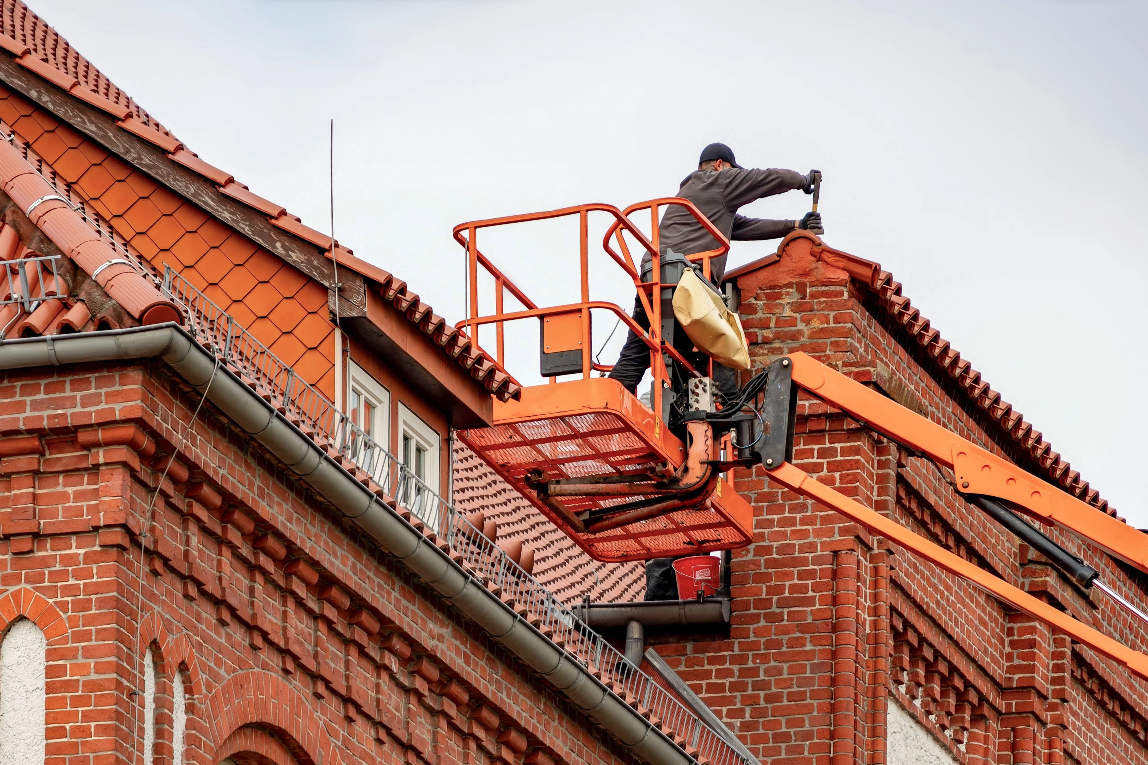 Tradesperson carrying out guttering maintenance on a brick residential property